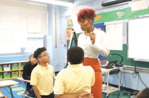 Teacher in front of class speaking to student