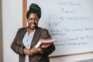 Female student in front of whiteboard holding a book