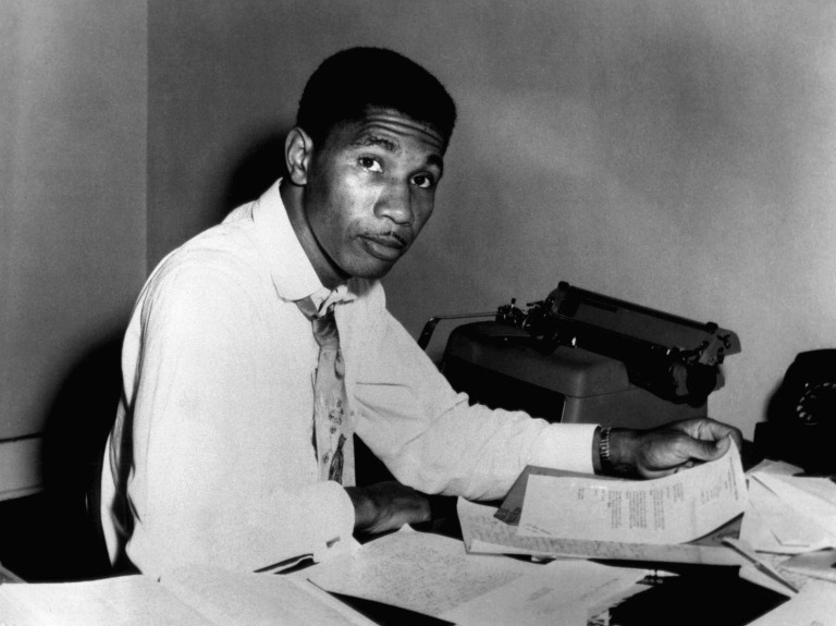Medgar Evers sitting at a desk with a typewriter