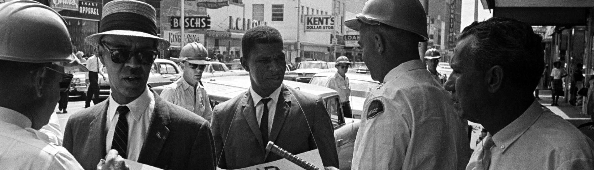 Medgar Evers wearing a sign that reads End Brutality in Jackson