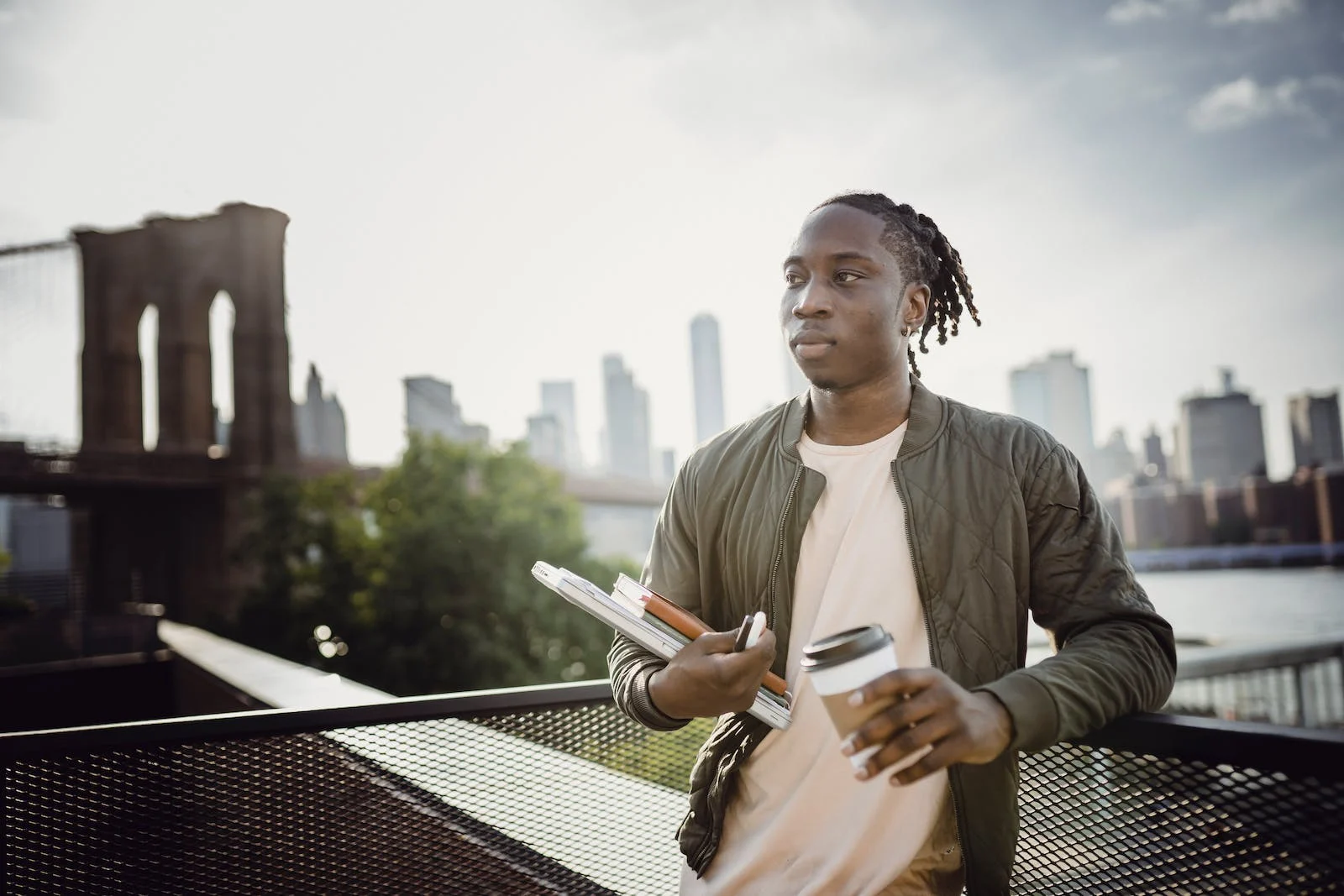 Male holding books with the Brooklyn Bridge in the background