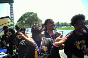 Senior Kayshaun Higgs celebrates the men's team title with teammates Michael Ortega and Zachary Bussey at Icahn Stadium on Randalls Island. (Nick Masuda/Office of Communications)