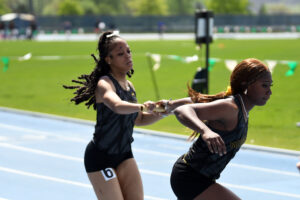 Shaniya Chung, left, and Tia Thompson make a successful handoff in the 4x400 women's relay at the CUNYAC Championships on May 3, 2025. The Cougars would win the race. (Nick Masuda/Office of Communications)