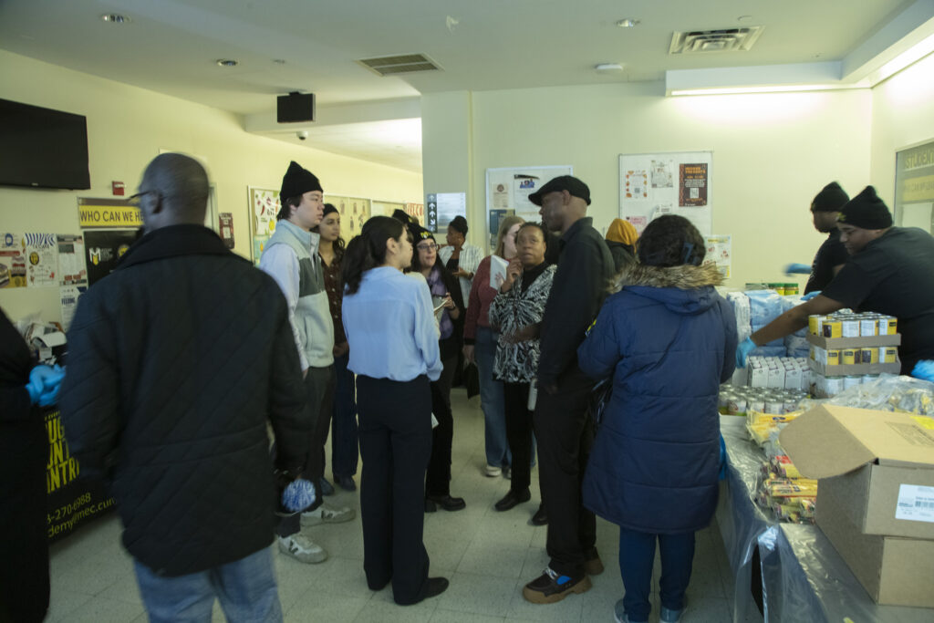 Transition Academy volunteers man tables as Dr. Waleek Boone (Transition Academy Director) explains nuances of the Cougar Country food pantry to members of the City Council Finance Department and CUNY Central. (Photo by Richard Joseph)