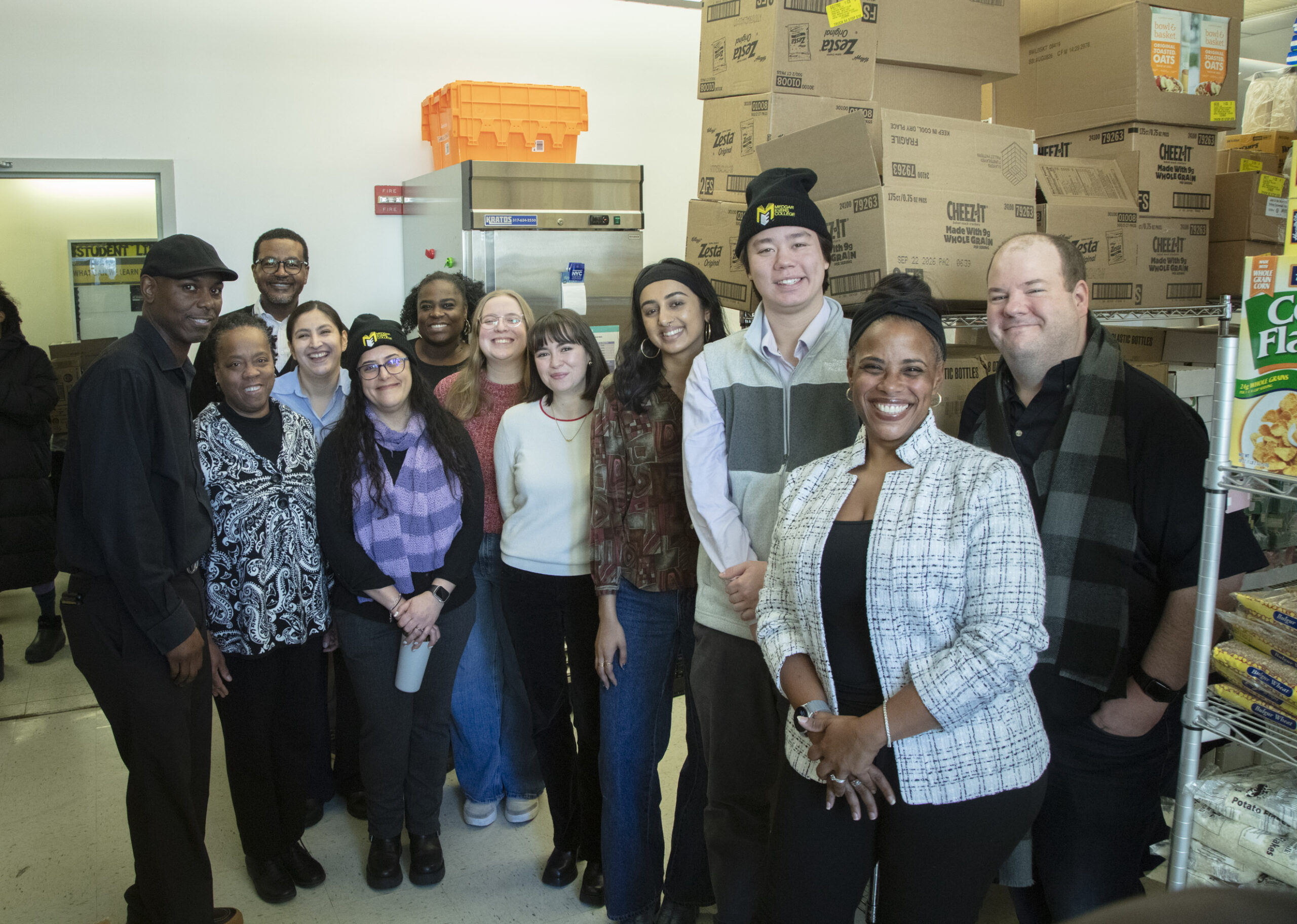 Dr. Waleek Boone (Transition Academy Director, front, left) is joined in the Cougar Country food pantry with members of the City Council Finance Department, CUNY Central and SVP Jesse Kane (far left, rear row), Dr. LaToya Blount (Medgar Evers College Dean of Students, far right, rear row) and Dr. Shirley de Peña (CUNY Central, front, second from right) (Photo by Richard Joseph)